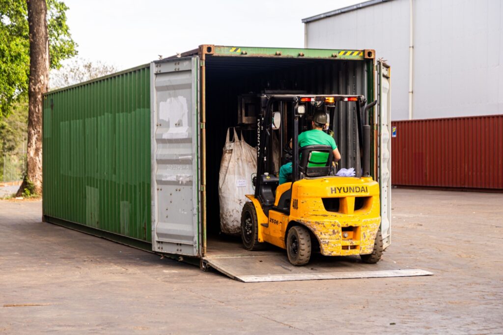 Montacargas cargando material compactado en contenedor para exportacion